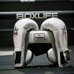 White boxing helmet and gloves inside a boxing ring with Boxlife branding, symbolizing sports and fitness.